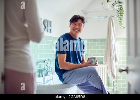 Reifes Asiatisches Paar Trägt Schlafanzug Sitzen Im Badezimmer Genießen Morgen Heiße Getränke Zusammen Stockfoto