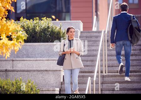 Geschäftsmann Und Geschäftsfrau, Die Im Freien Pendeln Und Schritte Auf Dem Weg Zur Arbeit Machen Stockfoto