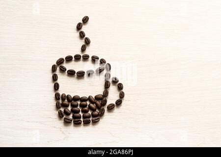 Geröstete Kaffeebohnen, die in Form einer Tasse Kaffee auf weißem Hintergrund platziert werden, kopieren Platz für Text Stockfoto