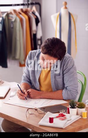 Männlicher Student Oder Geschäftsinhaber, Der In Modedesign-Designs Im Studio Arbeitet Stockfoto