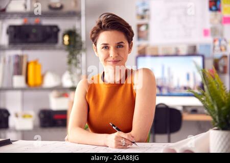 Porträt Einer Architektin Im Büro, Die Am Schreibtisch Arbeitet Und Notizen Zu Plan Oder Blueprint Macht Stockfoto