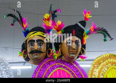 Santhal Stammesmasken von Mann und Frau mit bunten Federmützen, ausgestellt zum Verkauf auf der Kunsthandwerksmesse, Kalkutta, Westbengalen, Indien. Stockfoto