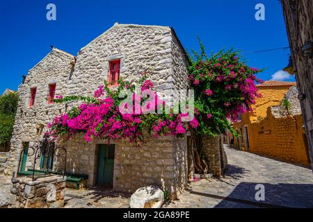 Wunderschön dekorierte Straßen der Stadt Areopoli mit bunten Blumen rund um die traditionellen stonierten Gebäude in Laconia, Griechenland Stockfoto