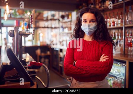 Porträt Einer Weiblichen Bararbeiterin Mit Gesichtsmaske Während Einer Gesundheitstpandemie, Die Hinter Dem Tresen Steht Stockfoto