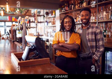 Porträt Eines Lächelnden Paares Mit Bar, Das Hinter Dem Counter Steht Stockfoto