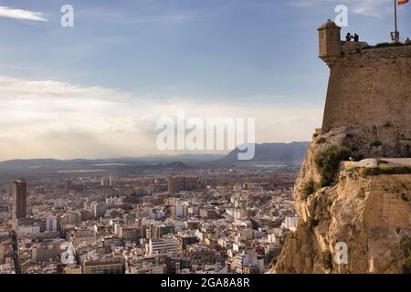 Ein Abschnitt der hohen Burgmauer der Burg Santa Barbara in Alicante, Spanien mit einem Eckturm, der die Stadt unten überblickt Stockfoto