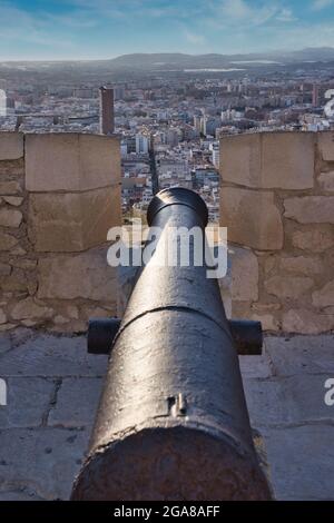 Eine alte Kanone auf der Burg Santa Barbara in Alicante, Spanien, zeigt von oben auf der Burgmauer über die Stadt Stockfoto