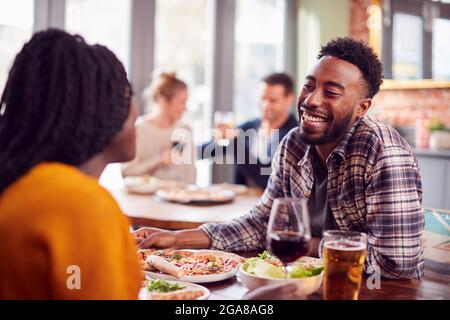 Lächelndes Junges Paar Auf Date, Das Gemeinsam Pizza Im Restaurant Genießt Stockfoto