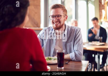 Lächelndes Junges Paar Auf Date, Das Gemeinsam Pizza Im Restaurant Genießt Stockfoto