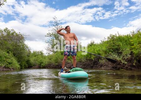 Abenteuerliche hispanische Erwachsene Athletic man Paddle Boarding Stockfoto