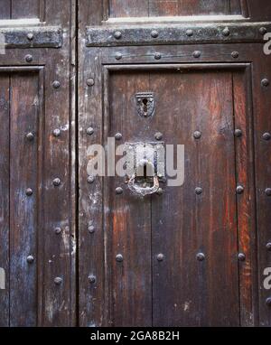 Schäbige Tür mit Schlüsselloch und Klopfer Stockfoto