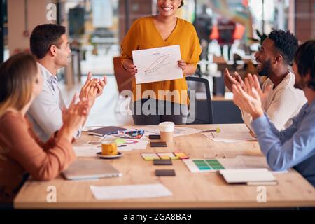 Kollegen Applaudieren Als Geschäftsfrau Gibt Präsentation In Modernen Open Plan Office Stockfoto