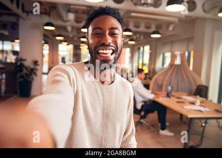 Porträt Eines Jungen Geschäftsmannes, Der Selfie Auf Dem Mobiltelefon Im Modernen Open Plan Office Nimmt Stockfoto