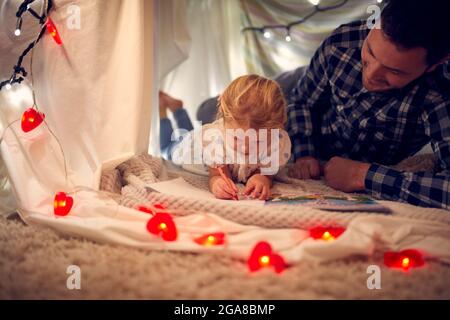 Vater und junge Tochter zeichnen Bild in hausgemachtem Lager im Kinderzimmer zu Hause Stockfoto