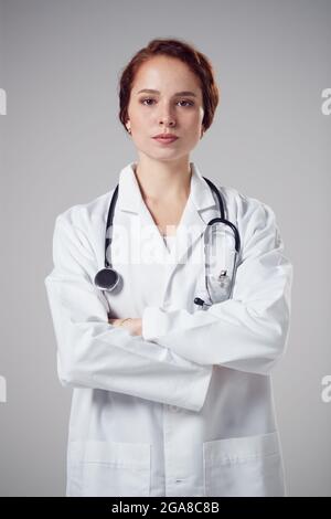 Studio Portrait Von Serious Young Doctor Trägt Weißen Mantel Gegen Einfachen Hintergrund Stockfoto