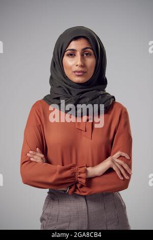Studio Portrait Einer Ernsthaften Jungen Geschäftsfrau Mit Gefalteten Armen Und Kopftuch Vor Einfarbigem Hintergrund Stockfoto