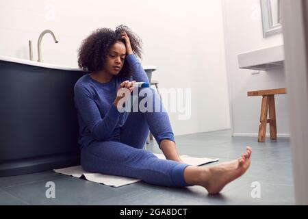 Enttäuschte Frau Sitzt Auf Dem Boden Im Badezimmer Zu Hause Mit Negativen Home Schwangerschaft Test Stockfoto