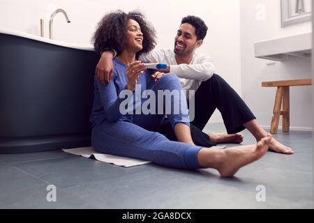 Aufgeregt Paar Sitzt Auf Dem Boden Im Badezimmer Zu Hause Mit Positiven Home Schwangerschaft Test Stockfoto