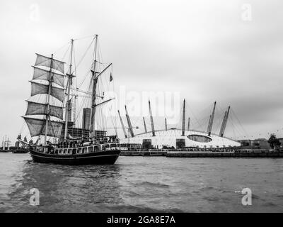 Ein dreimastiger Hochschiff auf der Themse im Großraum London, Großbritannien, mit der O2-Kuppel im Hintergrund, in Schwarz und Weiß. Fotografiert während des Th Stockfoto