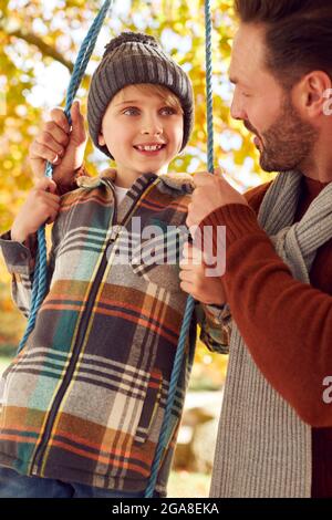 Vater Schiebt Sohn Mit Spaß Auf Seil Schwingen Im Herbstgarten Stockfoto