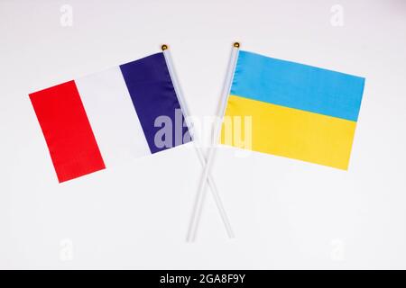 Die Flagge Frankreichs und die Flagge der Ukraine kreuzten sich auf weißem Hintergrund. Isoliert. Das Bild veranschaulicht die Beziehung zwischen den Ländern Stockfoto