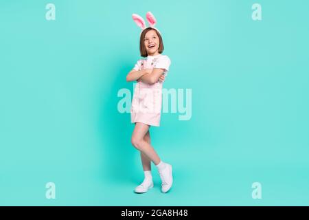 Foto von ziemlich liebenswert schulmädchen gekleidet insgesamt Kaninchen Ohren Arme gekreuzt suchen leeren Raum isoliert türkis Farbe Hintergrund Stockfoto