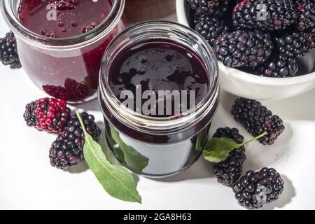 Süße hausgemachte Brombeermarmelade in einem kleinen Glas auf weißem Hintergrund, mit frischen Beeren kopieren Platz Stockfoto