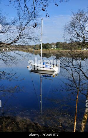 Spiegelung einer Yacht, die am ruhigen, ruhigen Beaulieu-Fluss in der Nähe von Bucklers Hard in Hampshire, England, Großbritannien, festgemacht ist. Stockfoto