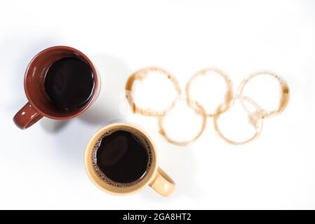 Kaffeebecher mit olympischen Ringen aus Kaffeeflecken auf weißer Oberfläche Stockfoto