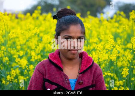 TIKAMGARH, MADHYA PRADESH, INDIEN - 23. JULI 2021: Indisches Dorfmädchen auf schwarzem Senffeld. Stockfoto