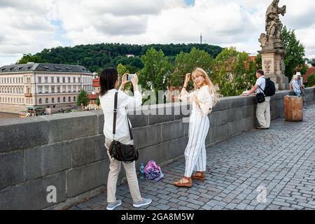 13. August 2017 Prag, Tschechische Republik. Asiatische Touristen werden vor dem Hintergrund der Sehenswürdigkeiten der Stadt fotografiert. Paare nehmen Selfies dagegen Stockfoto