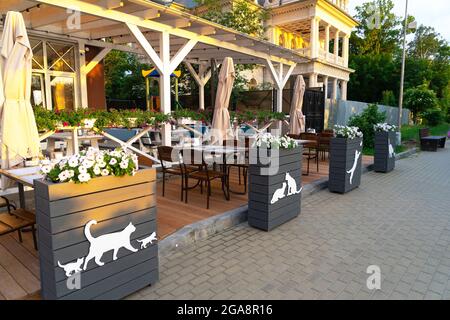 Ein leeres Straßencafé mit Silhouetten von Katzen und Kätzchen auf Vasen mit Petunien-Blumen auf der Promenade der Stadt Zelenogradsk Stockfoto