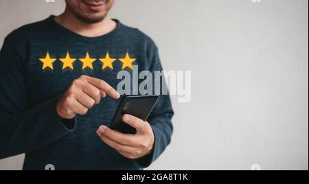 Smartphone mit Kundenhand und fünf Sternen mit Kopierplatz. Best Excellent Services Bewertung für Zufriedenheit.Customer Experience Satisfaction con Stockfoto