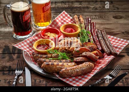 Bratwürste, Kartoffelkeile, gedünstetes Kohl, Saucen als Biersnack Stockfoto