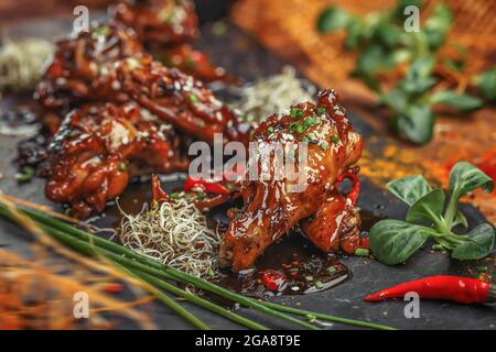 Gebackene Hähnchenflügel und -Beine mit Sesam in Honig-Senfsauce mit indischen Gewürzen. Das Konzept der indischen Küche. Stockfoto
