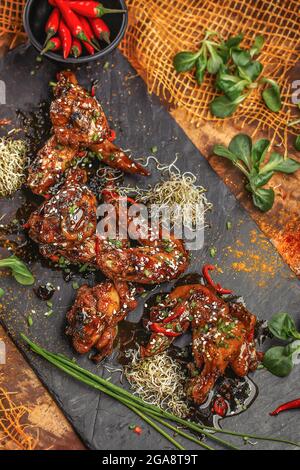 Gebackene Hähnchenflügel und -Beine mit Sesam in Honig-Senfsauce mit indischen Gewürzen. Das Konzept der indischen Küche. Stockfoto