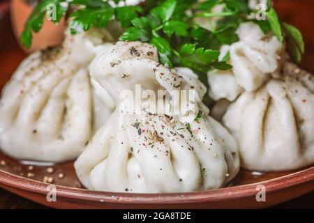 Georgische traditionelle Knödel khinkali mit Fleisch, Gewürzen und Gemüse auf einem Steinzeugteller Stockfoto