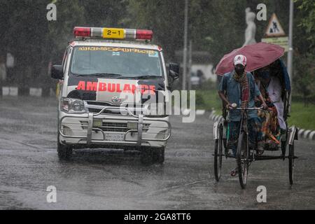 Dhaka, Bangladesch. Juli 2021. Ein Rikscha-Abzieher sah während eines regnerischen Tages inmitten der covid-19-Sperre die Straße entlang fahren.das Land wurde streng gesperrt und schwerer Monsunregen verursachte extreme Wassereinschläge in den meisten Gebieten der Stadt Dhaka. Die Straßen waren unter Wasser, was die Reise langsam und gefährlich machte. (Foto: Sazzad Hossain/SOPA Images/Sipa USA) Quelle: SIPA USA/Alamy Live News Stockfoto