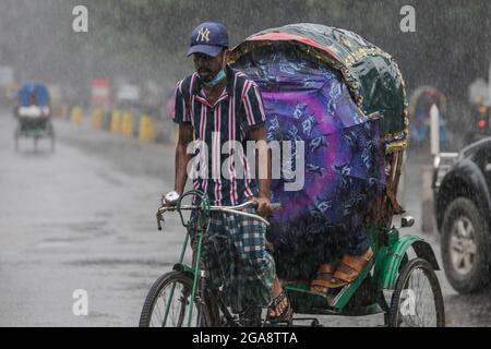 Dhaka, Bangladesch. Juli 2021. Ein Rikscha-Abzieher sah während eines regnerischen Tages inmitten der covid-19-Sperre die Straße entlang fahren.das Land wurde streng gesperrt und schwerer Monsunregen verursachte extreme Wassereinschläge in den meisten Gebieten der Stadt Dhaka. Die Straßen waren unter Wasser, was die Reise langsam und gefährlich machte. (Foto: Sazzad Hossain/SOPA Images/Sipa USA) Quelle: SIPA USA/Alamy Live News Stockfoto