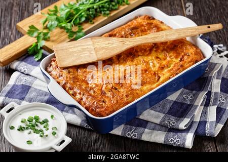 Pikante kartoffelkugel, gebackener Pudding oder Auflauf geriebener Kartoffeln in einer Auflaufform auf einem Holztisch, jüdisches Feiertagsrezept, Nahaufnahme Stockfoto