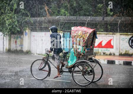 Dhaka, Bangladesch. Juli 2021. Ein Rikscha-Abzieher sah während eines regnerischen Tages inmitten der covid-19-Sperre die Straße entlang fahren.das Land wurde streng gesperrt und schwerer Monsunregen verursachte extreme Wassereinschläge in den meisten Gebieten der Stadt Dhaka. Die Straßen waren unter Wasser, was die Reise langsam und gefährlich machte. (Foto: Sazzad Hossain/SOPA Images/Sipa USA) Quelle: SIPA USA/Alamy Live News Stockfoto