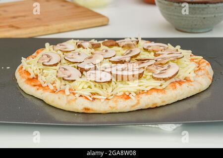 Roher Pizzateig mit Tomatensauce, Mozzarella und Crimini-Nushroom-Scheiben. Schritt für Schritt Backprozess, Rezept Stockfoto