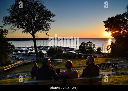 Menschen entspannen sich auf Bänken im Park, beobachten herrlichen Sonnenuntergang, Blick auf den Hafen mit Booten, in Egg Harbor, Door County, Wisconsin, USA Stockfoto