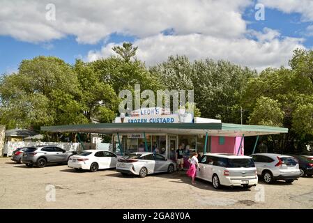 Autos und andere Fahrzeuge, die bei Leon's Frozen Custard geparkt sind, wo Kunden nach Bestellungen in Fahrzeugen, Oshkosh, WI, USA, Pudding und Fast Food essen Stockfoto