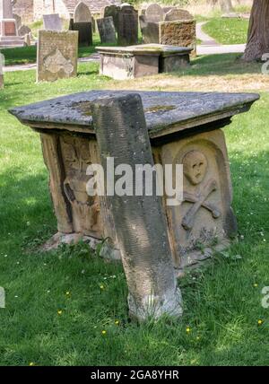 Ein unverwechselbares Denkmal in Form eines Schädels und Kreuzknochen im Pestdorf Eyam in Derbyshire. Stockfoto