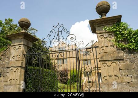 Markante Tore zur Hall im Pestdorf Eyam in Derbyshire. Schmiedeeiserne Tore und riesige Steinsäulen bieten einen beeindruckenden Eingang. Stockfoto