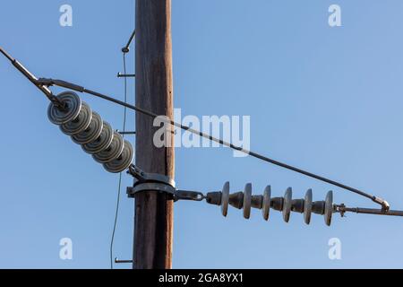 Foto eines hölzernen Telefonpfostens und Kabel vor einem blauen Himmel Stockfoto