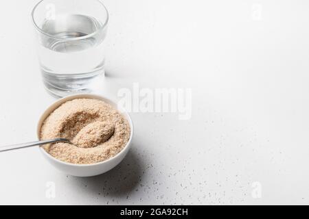 Psylliumschalen und Glas wasserlösliche Ballaststoffe ergänzen für Darm auf weißem Hintergrund. Superfood für gesunde, senkt den Cholesterinspiegel, gleicht BL Stockfoto