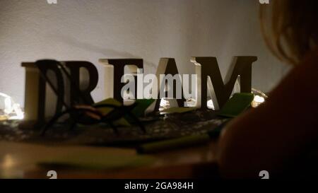 Holzbuchstaben, die den TRAUM auf einem beleuchteten Tisch ausschreiben Stockfoto
