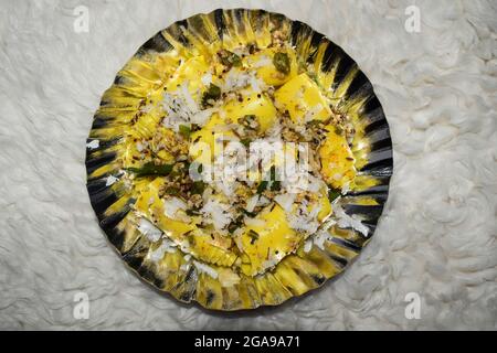 Khandvi ein traditionelles und authentisches Gujarati-Gericht, das als herzhafte Snacks serviert wird. Temperiert und garniert mit geriebener Kokosnuss, grünem Chilly und Sesam Stockfoto